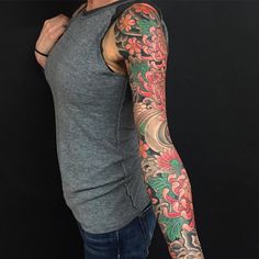 a man with a tattoo on his arm and shoulder is standing in front of a black background