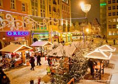 people are walking around in the snow near shops and buildings at night, with lights on