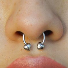 a close up of a woman's nose with two heart shaped piercings on it