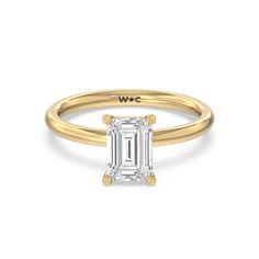 a yellow gold ring with an emerald cut diamond in the center, on a white background