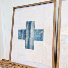 two framed art pieces with blue and white designs on them, one in wood frame the other in linen