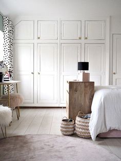 a bedroom with white closets and black polka dot wallpaper on the walls, along with baskets