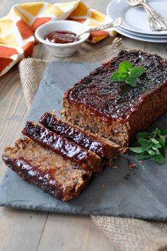 sliced meatloaf with sauce and herbs on slate board