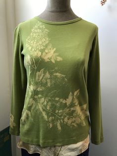 a green shirt with white flowers on it is sitting on a mannequin's head