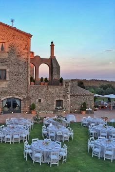 an outdoor dining area with tables, chairs and umbrellas set up in front of a stone building