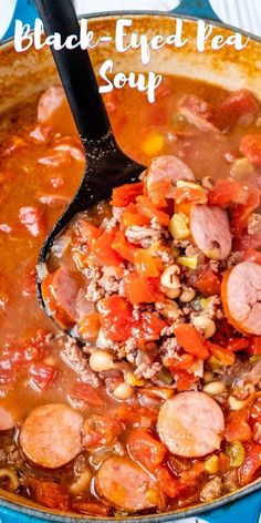 a spoon full of soup with sausage and beans in it on top of a blue plate