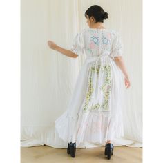 a woman in a white dress is standing on a wooden floor and looking at the wall