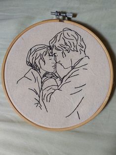 a couple kissing each other in front of a embroidery hoop