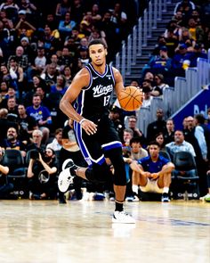 a basketball player dribbling the ball down the court during a game with an audience watching