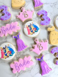 decorated cookies are arranged on a marble countertop with the names of princesses and tiaras