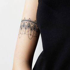 a woman's arm with a tattoo on it that has an intricate design and is wearing a black dress