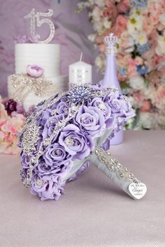 a bouquet of purple flowers sitting on top of a table next to a wedding cake