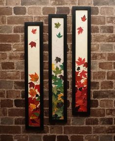 three framed art pieces on a brick wall with autumn leaves painted on the back and sides