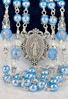 Austrian Crystal pearls make this Heavenly sky blue rosary with sterling silver plated filigree bead caps perfect for a bridal bouquet or any special gift or occasion. If you are looking for Swarovski pearls, look no further! I use these interchangeably with my Swarovski light blue pearls and they match perfectly. They're the perfect substitute since Swarovski exited the market. The crucifix and centerpiece of the Miraculous Medal are both die cast oxidized silver and made in Italy. It can be pe Blue Spiritual Jewelry For First Communion, Blue Spiritual Jewelry For Wedding, Blue Spiritual Jewelry For Weddings, Heavenly Sky, Blue Rosary, Blue Pearls, Pearl Rosary, Catholic Wedding, Miraculous Medal