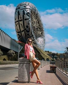 a woman sitting on top of a cement block next to a large metal object in the background