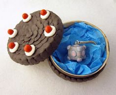 two cookies with red and white decorations are in a round box on top of blue tissue paper