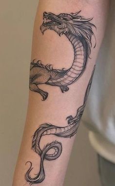 a black and white dragon tattoo on the arm