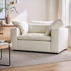 a living room with a white couch, table and vases on the side tables