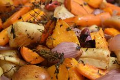 a pile of potatoes and carrots with herbs