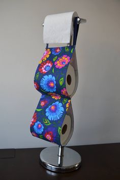 two rolls of toilet paper sitting on top of a metal holder with floral fabric covering