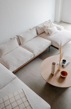 a living room filled with white couches and wooden coffee table next to a window