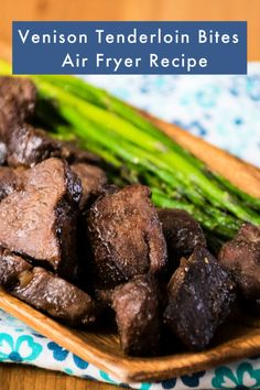 a wooden plate topped with meat and asparagus on top of a blue and white towel