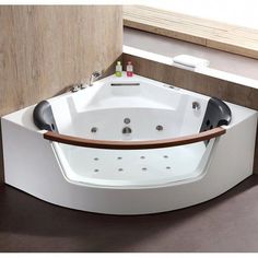 a large white bath tub sitting on top of a wooden floor next to a window