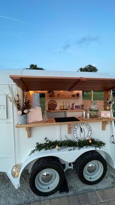 a food truck is decorated with greenery and lights on the outside, along with an outdoor kitchen