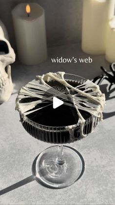 a glass filled with liquid sitting on top of a table next to candles and skulls