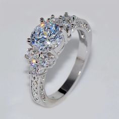 a diamond ring with three stones on the side and one stone in the middle, surrounded by diamonds