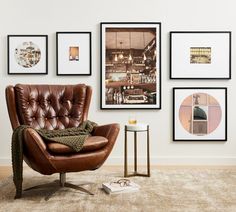 a brown leather chair sitting in front of a wall with pictures hanging on it's walls