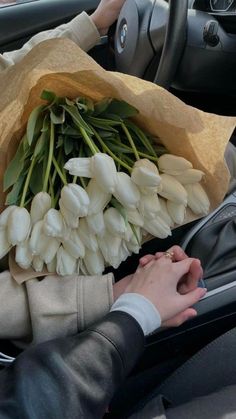 a bunch of flowers that are sitting in the passenger seat of a car, being held by someone's hand