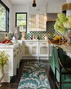 a kitchen with white cabinets and green accents on the countertops, along with an area rug