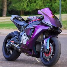 a purple motorcycle is parked on the side of the road in front of some trees