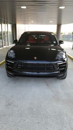 the front end of a black porsche parked in an empty parking garage with no one around