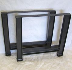 three black metal frames sitting on top of a white cloth covered floor next to each other