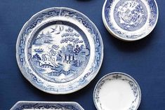 blue and white plates with designs on them sitting on top of a blue table cloth