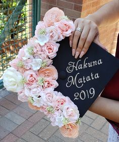 a person holding a graduation cap with flowers around it and the words hakkama matata written on it