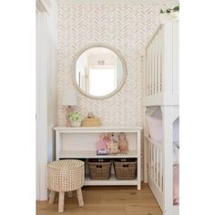 a baby's room with pink and white wallpaper, wooden flooring and a large round mirror on the wall