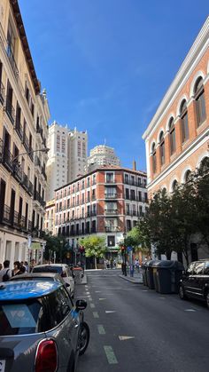 cars are parked on the street in front of tall buildings