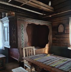 an old wooden table and chair in a room with wood paneling on the walls