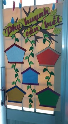 a door decorated with different colored bird houses and trees on it's side, hanging from the ceiling