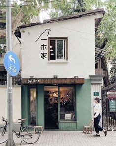 a man walking past a building with chinese writing on it's front door and windows