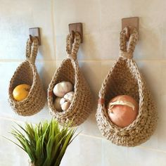 there are three baskets hanging on the wall next to a potted plant and an orange