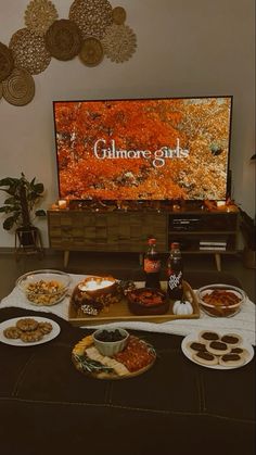 a table with food and drinks on it in front of a large screen tv that reads glimmore gad