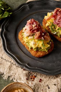 two open faced sandwiches on a black plate