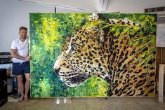 a man standing in front of a large painting with a cheetah on it