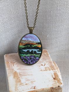 a necklace that is sitting on top of a piece of wood with purple flowers in it