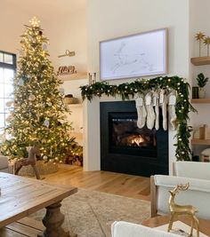 a living room with a christmas tree and fireplace decorated for the holiday season in white stockings