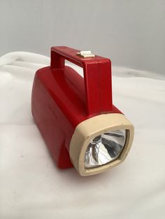 a red and white light sitting on top of a white sheet covered floor next to a wall